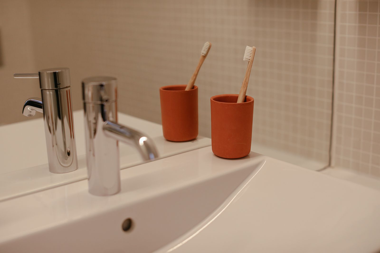 Clean bathroom sink with toothbrushes and cups
