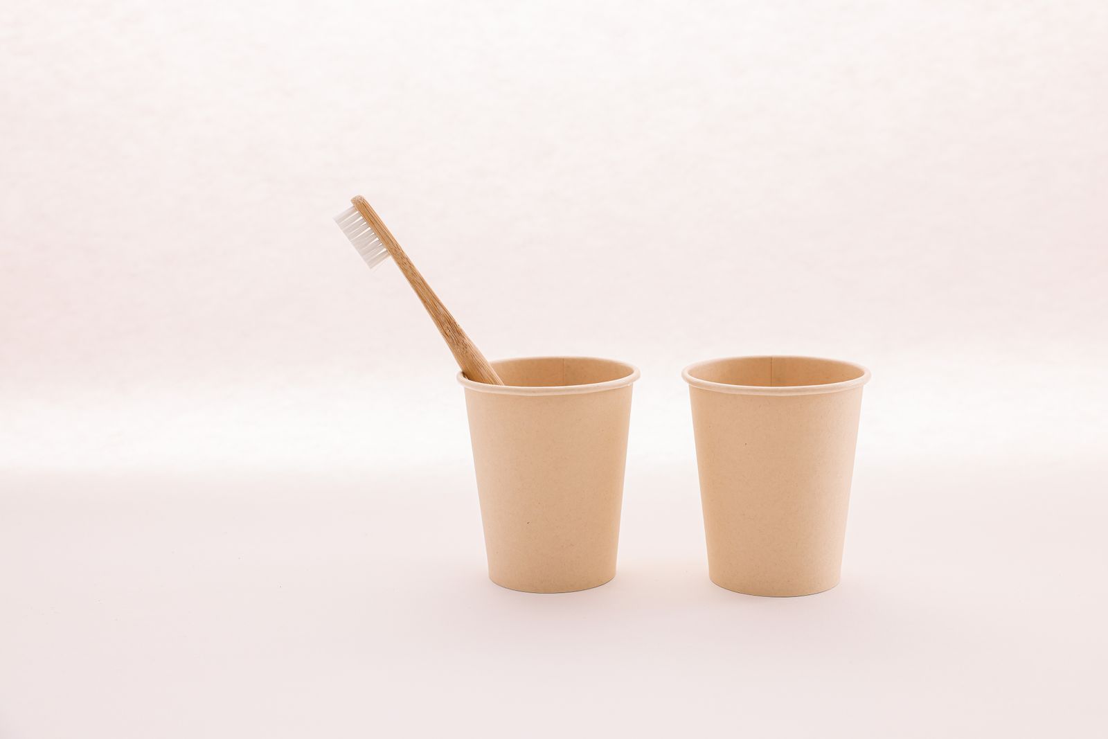Paper cups with a bamboo toothbrush on a table